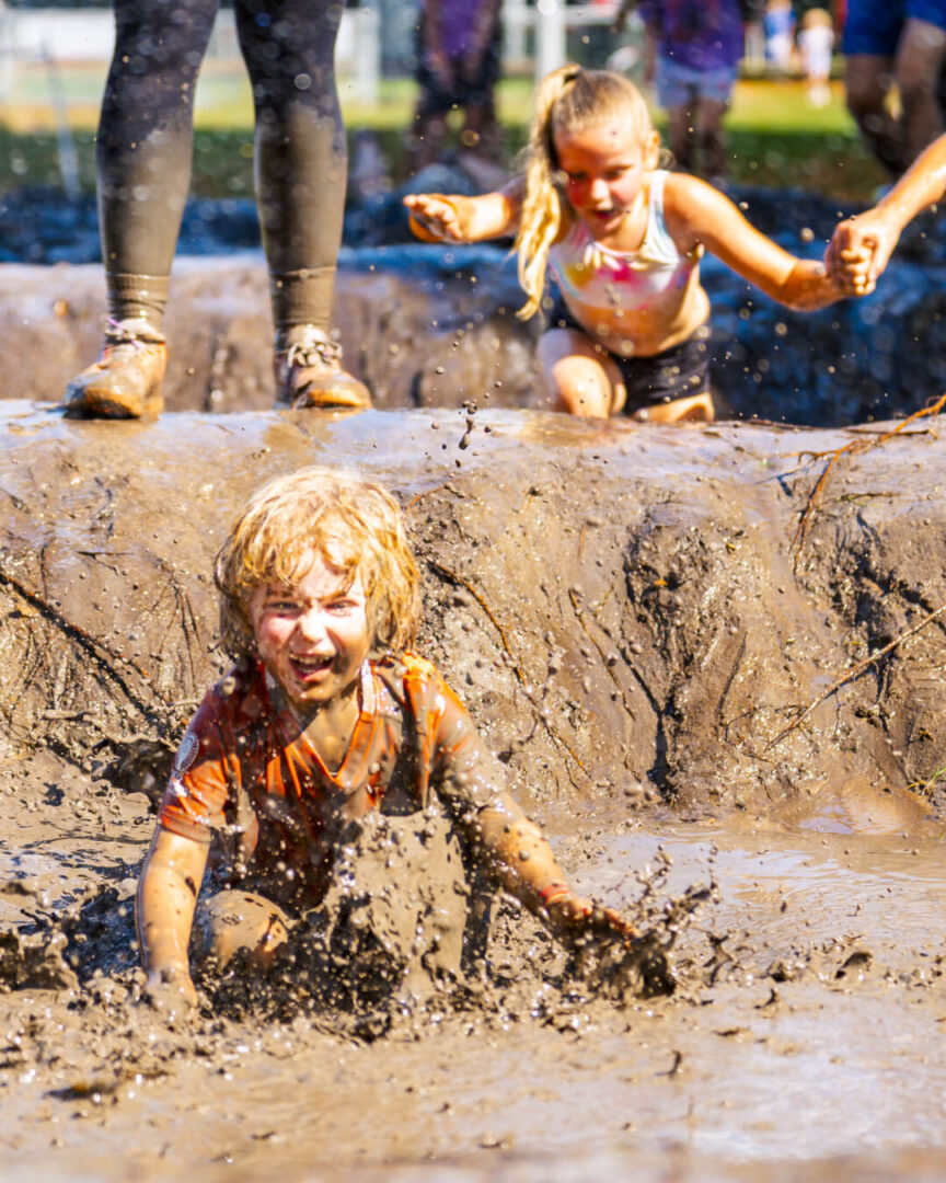 Deelnemers in modder tijden Obstacle Run voor kinderen in Hellendoorn
